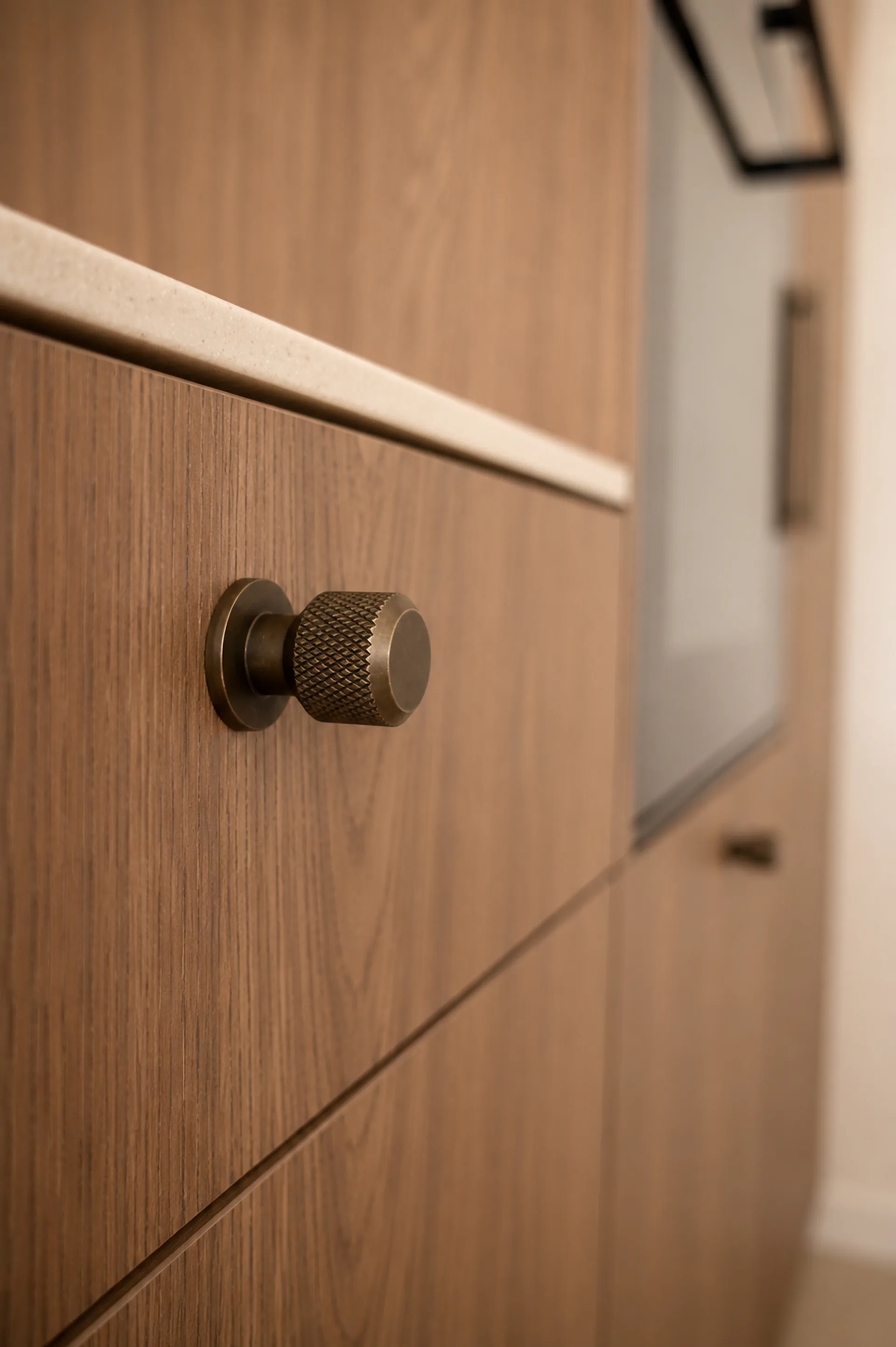 Detail van maatwerkkast in walnootfineer met bronzen knop