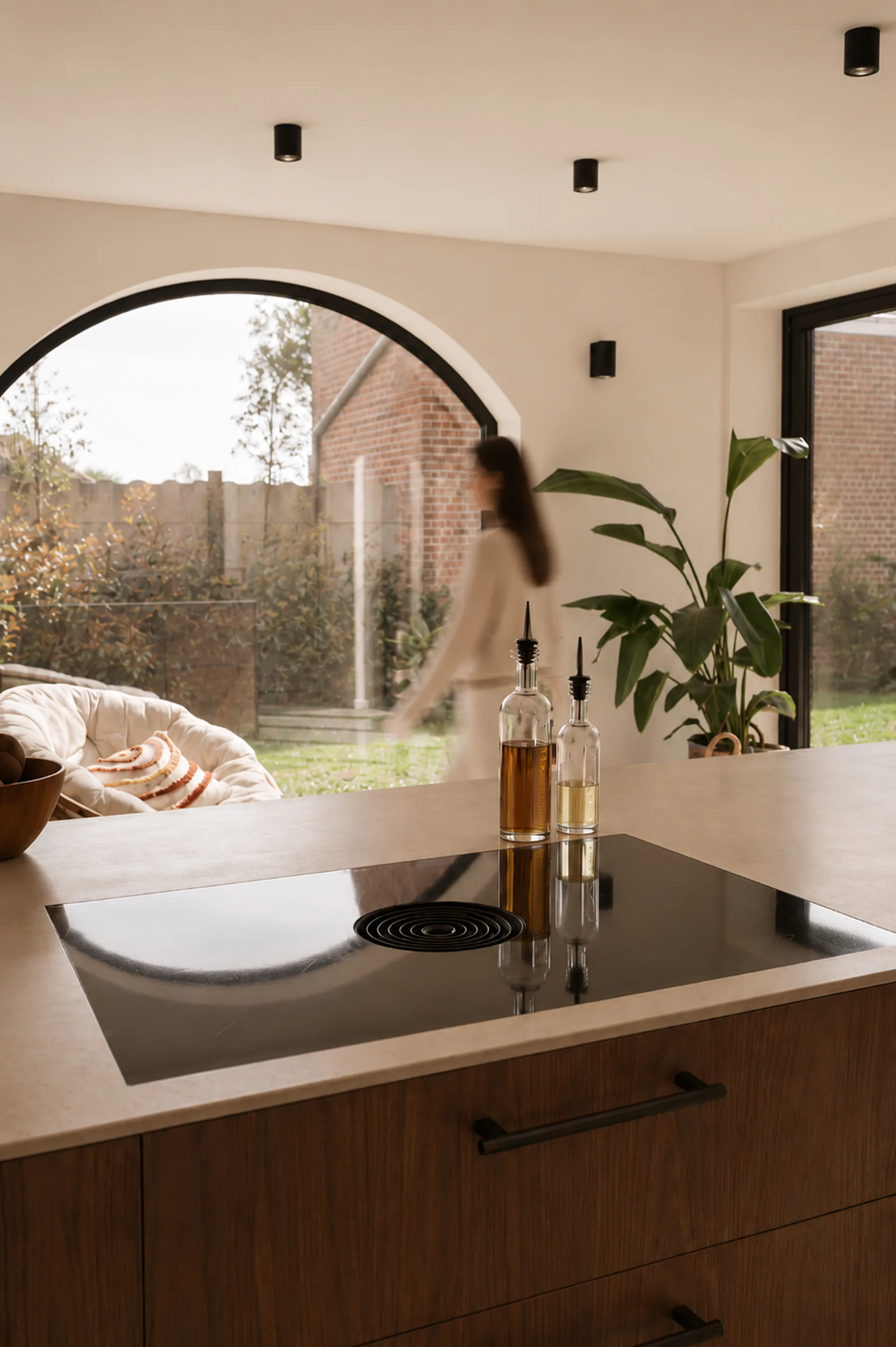Keuken op maat met inductie-eiland en boogvenster naar de tuin
